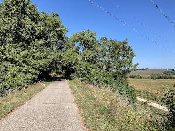 Slopes and hills are visible from the trail. The trail itself is flat (it's on a former rail line)